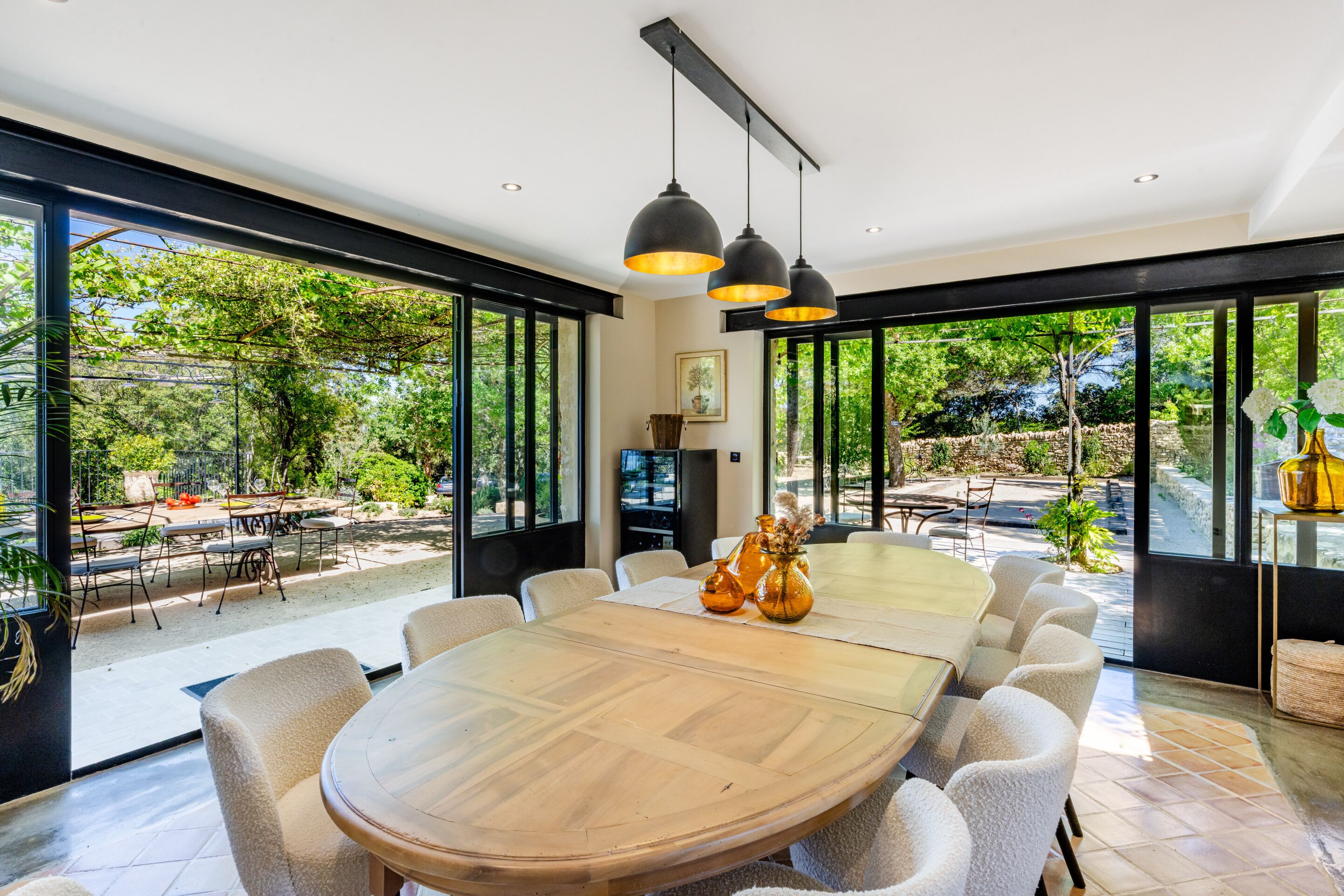 A modern dining area with a large wooden table, comfortable chairs, and pendant lighting.