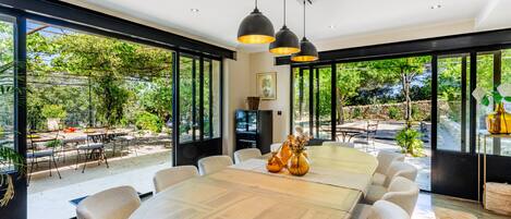 A modern dining area with a large wooden table, comfortable chairs, and pendant lighting.