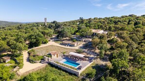 Una villa con piscina, rodeada de exuberante vegetación y un paisaje montañoso.