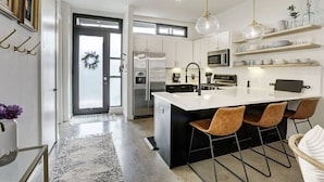 A modern kitchen with a central island, stainless steel appliances, and a black and white color scheme. - Lamar Treehouse (Austin)