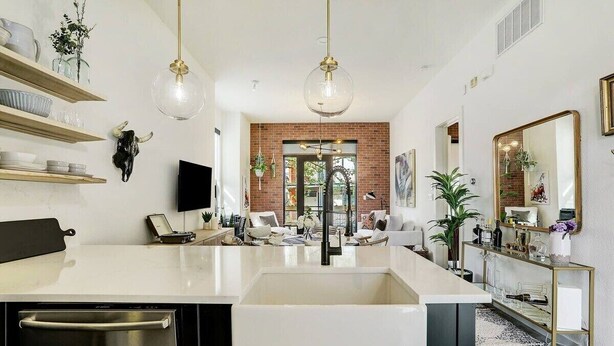 A modern kitchen with a large island, stainless steel appliances, and hanging pendant lights. - Lamar Treehouse (Austin)