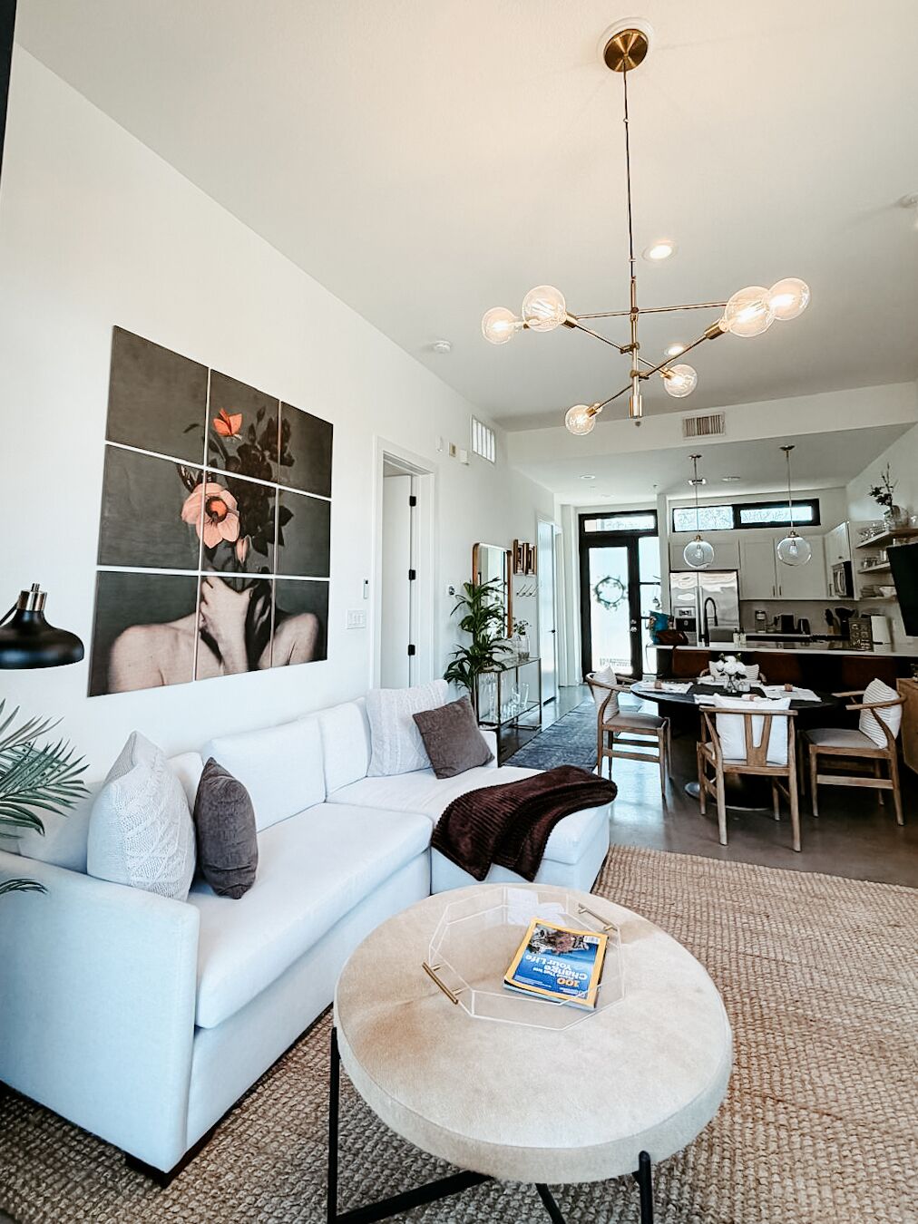 A modern living room with a white sofa, a round coffee table, and a large abstract painting on the wall.