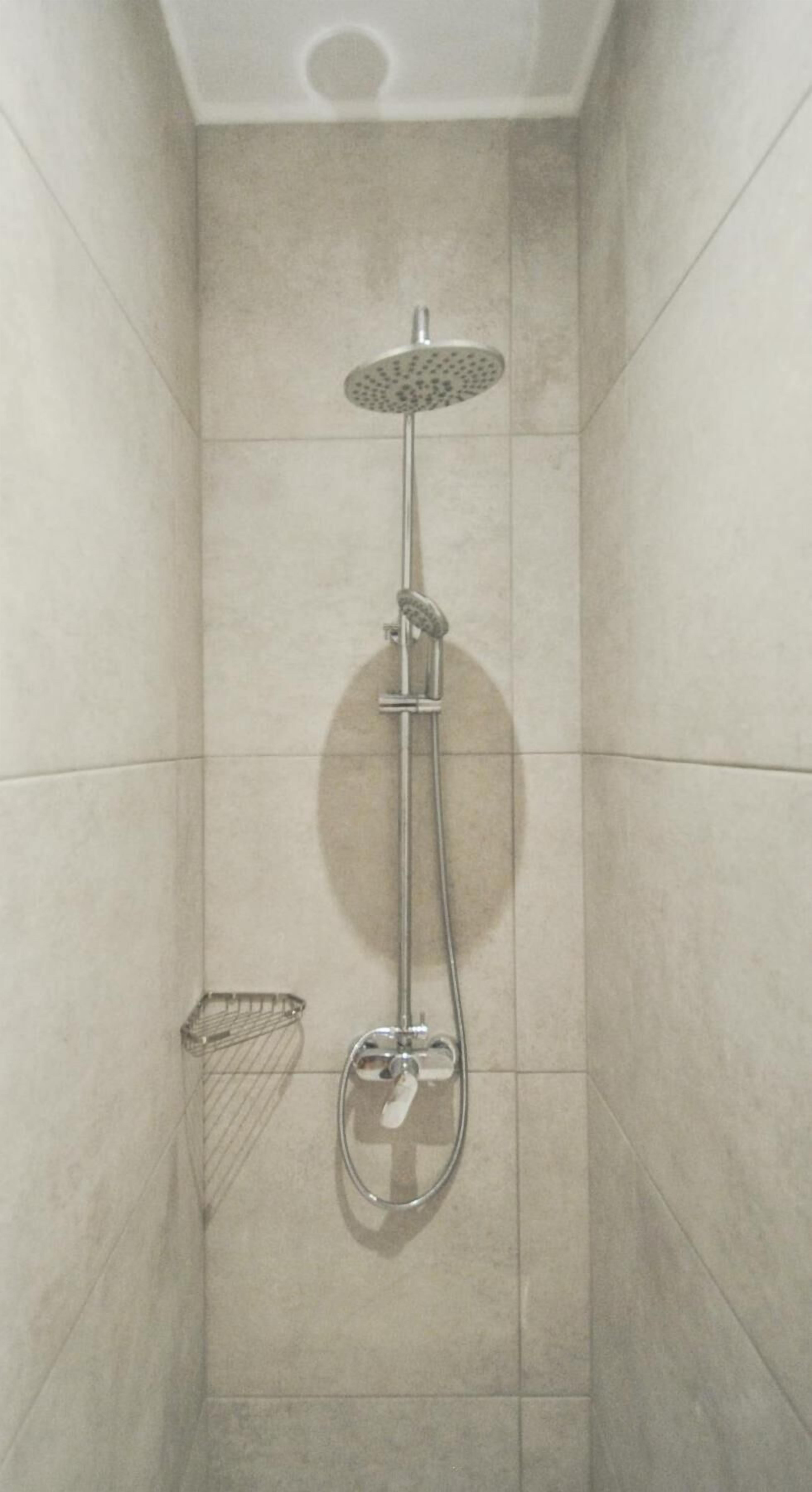 A shower with a handheld showerhead and a wall-mounted faucet.