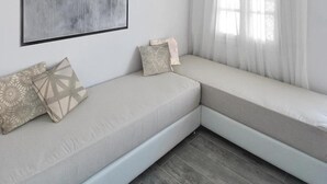 Una habitación moderna y minimalista con un banco empotrado, un cuadro abstracto grande y una ventana con cortinas translúcidas.
