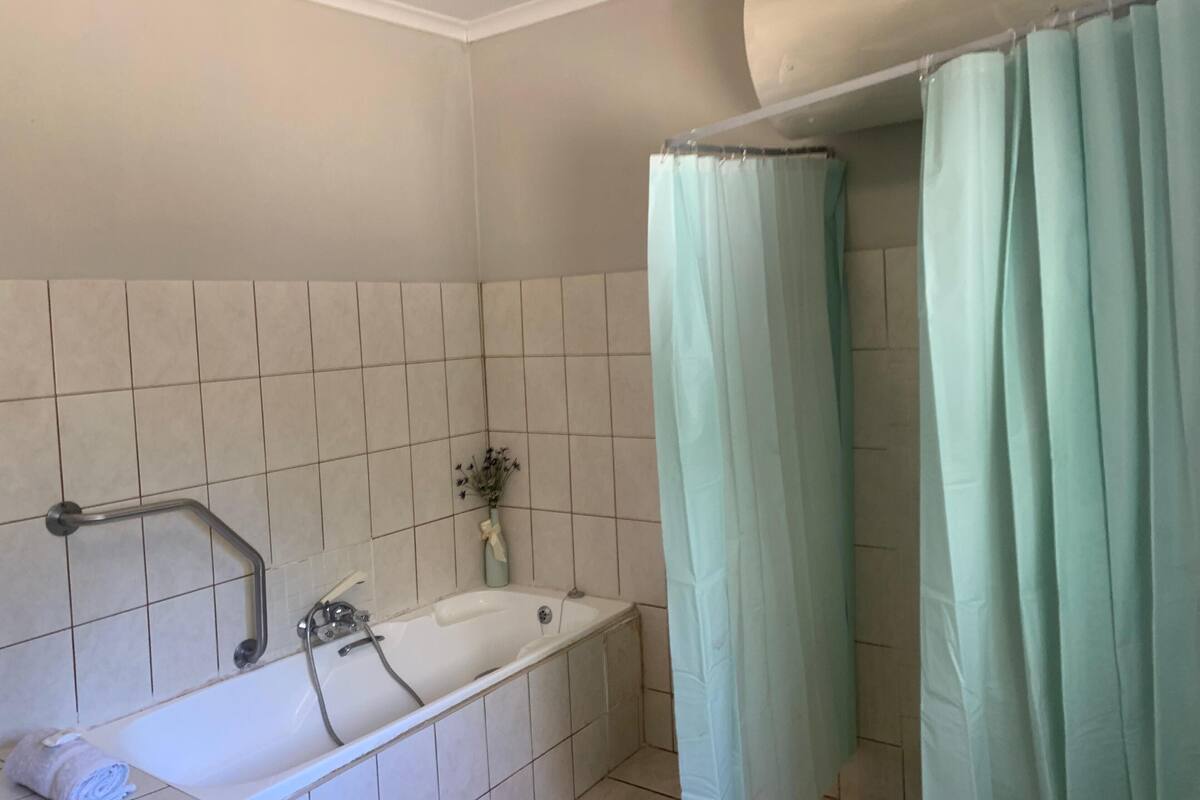 Un baño con bañera, cortina de ducha y barandilla.