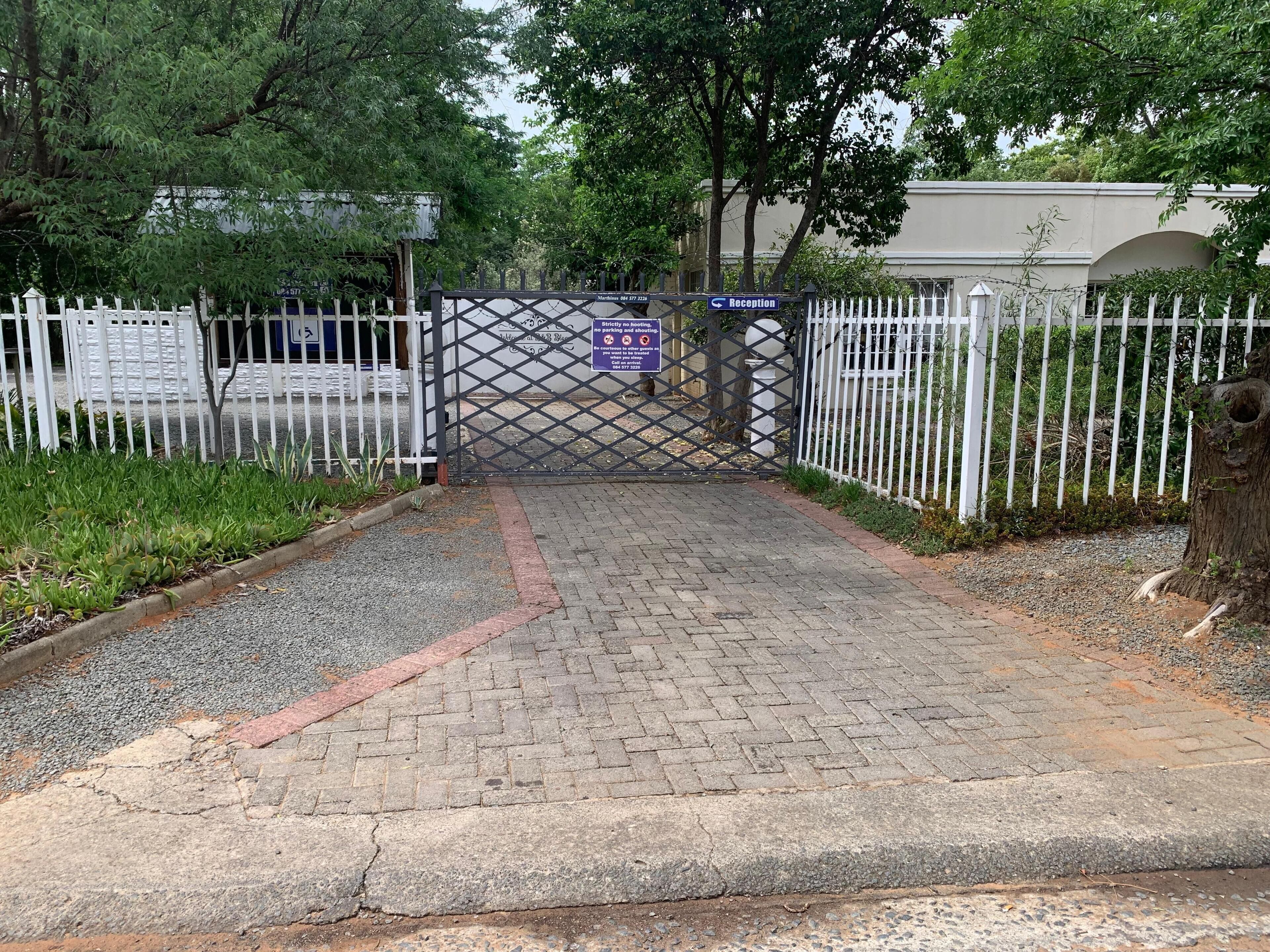 A gated entrance with a reception sign, a paved pathway, and a white fence.