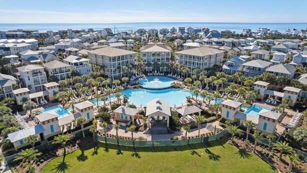 A resort with multiple buildings, a central pool, and a view of the ocean. - Sandy Cheeks - Stunning 4 Bedroom with 4 bikes & seconds to the Resort Pool! (Panama City Beach)