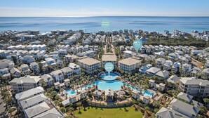 A coastal residential area with a central community pool surrounded by multi-story houses, beach access, and a clear view of the ocean. - Sandy Cheeks - Stunning 4 Bedroom with 4 bikes & seconds to the Resort Pool! (Panama City Beach)