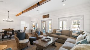 A spacious living room with a large sectional sofa, a coffee table, and wicker chairs. - Sandy Cheeks - Stunning 4 Bedroom with 4 bikes & seconds to the Resort Pool! (Panama City Beach)