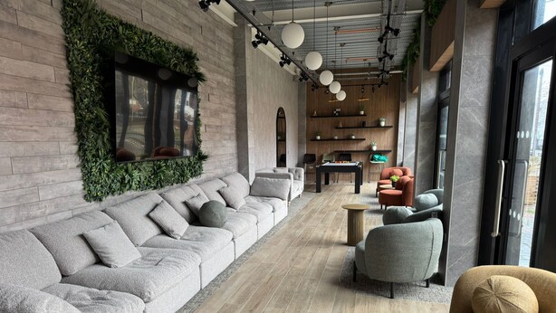 A modern lounge area with a grey sectional sofa, grey armchairs, and a small round table. - Modern & Spacious Studio Apartment in Leicester (Leicester)
