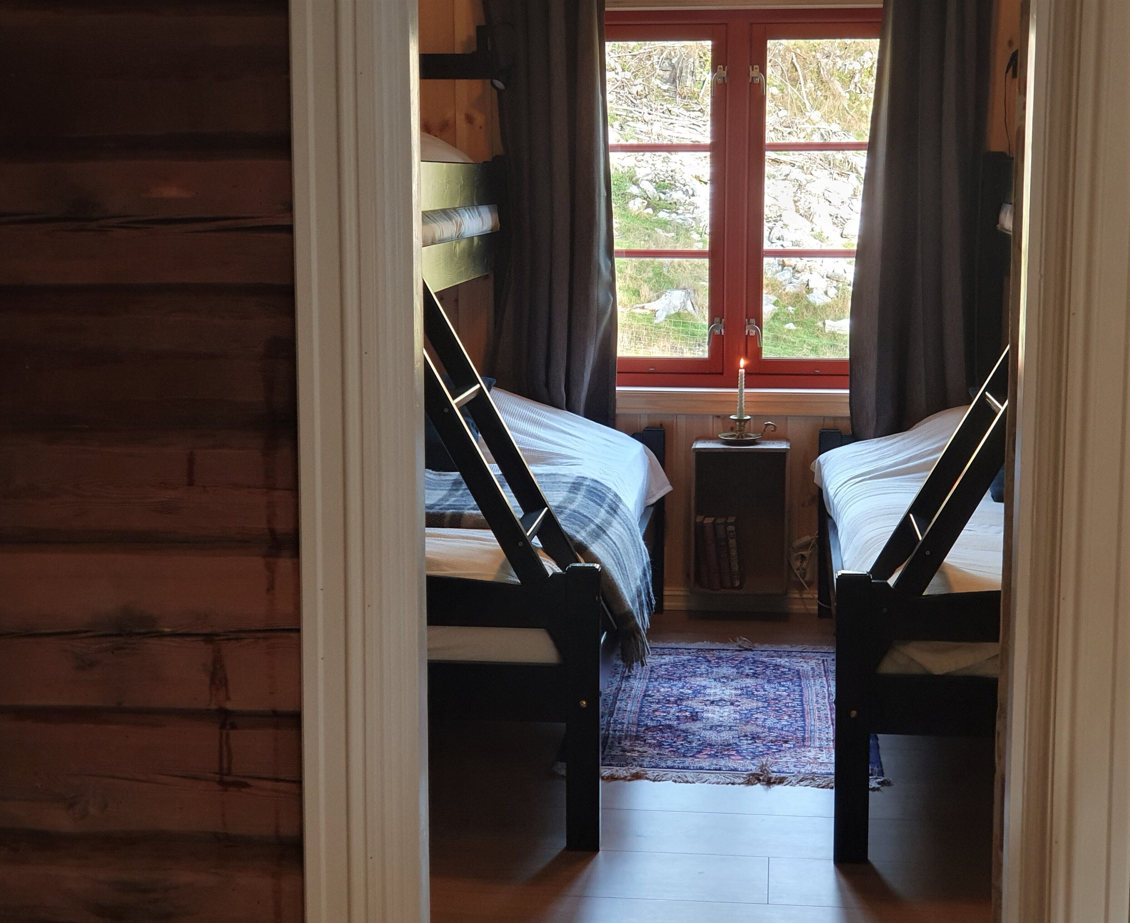 Una habitación con dos camas, una mesita con una vela y vistas al exterior a través de una ventana.