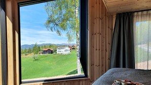 Una camera da letto con un'ampia finestra che si affaccia su un prato verde e delle case.