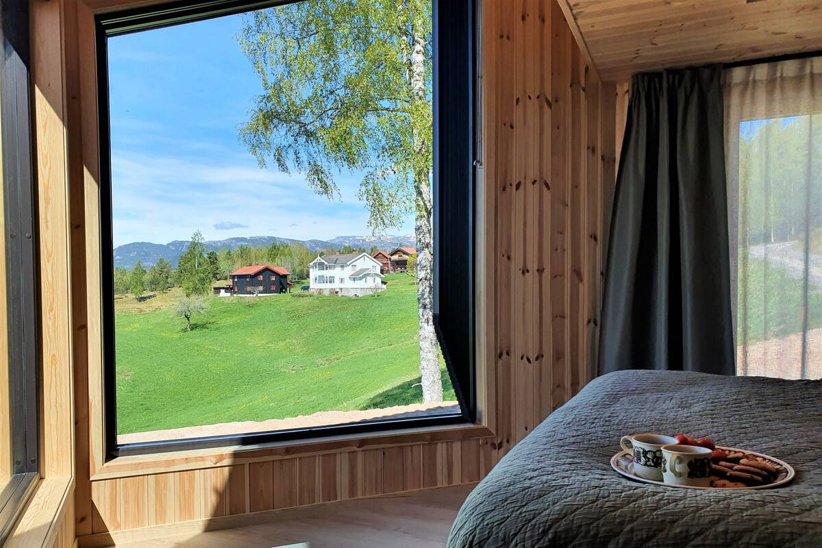 Un dormitorio con un ventanal que ofrece vistas a un campo verde y casas.