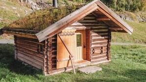 Una piccola baita di legno con tetto spiovente, una porta e una finestra.