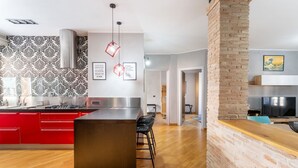 Een moderne keuken met rode kastjes, een centraal eiland en een wand betegeld met baksteen.