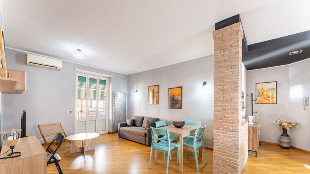 Een moderne woonkamer met een eethoek, een bank en een metselwerk accentmuur.