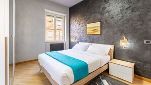 Een slaapkamer met een bed, nachtkastje en een raam.
