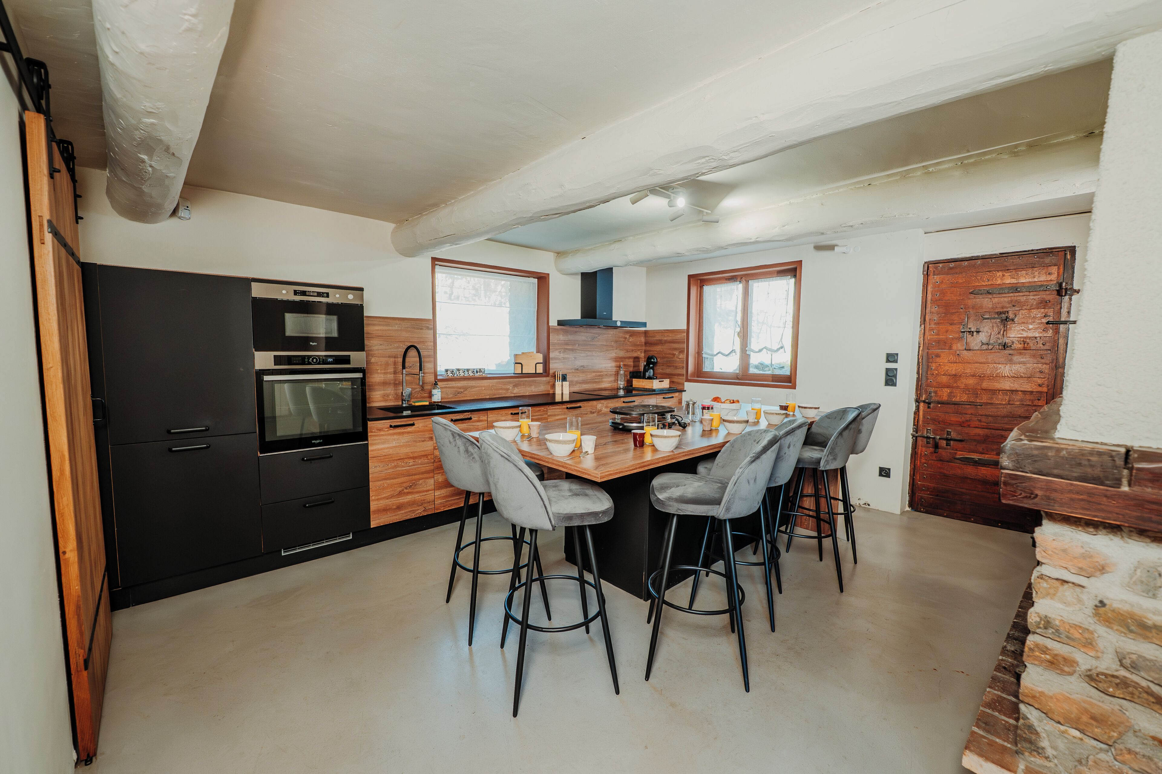 A modern kitchen with a central island, bar stools, and built-in appliances.