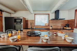 Una cocina moderna con una mesa de comedor preparada para el desayuno, incluyendo tazones, vasos y una estufa portátil.