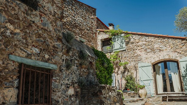 A stone building with a barred window, a wooden bench, and a potted plant. - Mas Sarava - Relaxation retreat, pilates & massage (Espira-de-l'Agly)