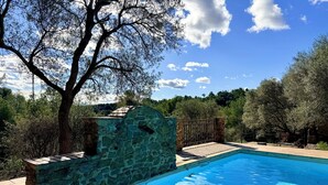 A swimming pool with stone walls, surrounded by trees and a stone fence. - Mas Sarava - Relaxation retreat, pilates & massage (Espira-de-l'Agly)