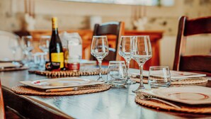 A dining table set with wine glasses, plates, and a bottle of wine. - Mas Sarava - Relaxation retreat, pilates & massage (Espira-de-l'Agly)