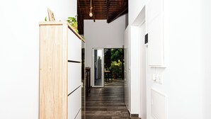 Eine Holztreppe führt zu einem Raum mit einer Schiebetür, weißen Wänden und einer Deckenleuchte.