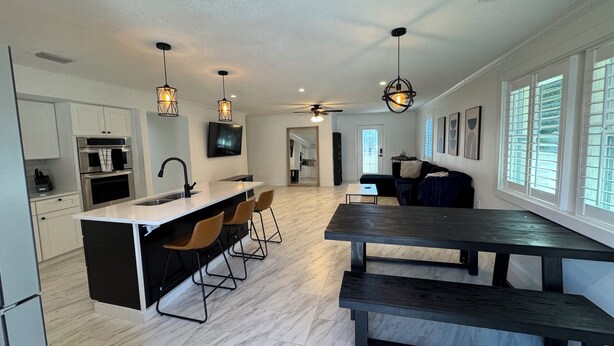 A modern kitchen with a central island, bar stools, and pendant lighting. - Modern South Tampa Retreat steps off Bayshore blvd, the bay is a minute away (Tampa)