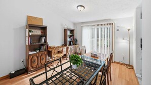 A dining area with a glass-top table, wooden chairs, a bookshelf, and a radiator. - Manassas Comfort Cozy 3br Family Home 3 Bedroom Home (Manassas)
