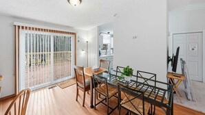 A modern dining area with a glass table, wooden chairs, and a potted plant. - Manassas Comfort Cozy 3br Family Home 3 Bedroom Home (Manassas)