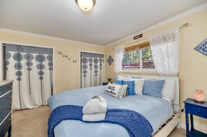 Une chambre à coucher avec un lit, une fenêtre avec des rideaux, un mur orné d’un motif décoratif et une inscription au-dessus de la fenêtre.
