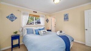 Ein Schlafzimmer mit Bett, Nachttisch, Fenster mit Vorhängen und Wanddekorationen.