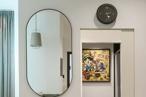 Une pièce dotée d’un grand miroir ovale, d’une horloge murale et d’une œuvre d’art encadrée.