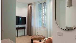 A modern room with a TV, a round coffee table, a sofa, and a window with curtains. - Milan Pop Art - new exclusive apartment (Milan)