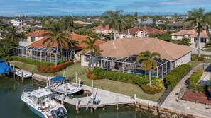 Ett bostadsområde med ett hus som har ett stort glashus, en brygga med båtar och utsikt över det omgivande området.