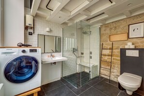 A modern bathroom with a glass-enclosed shower, a built-in washing machine, and a toilet. - AN IDEAL BLEND OF COMFORT, PARISIAN CHARM-JUST STEPS FROM PLACE DE LA RÉPUBLIQUE (Paris)