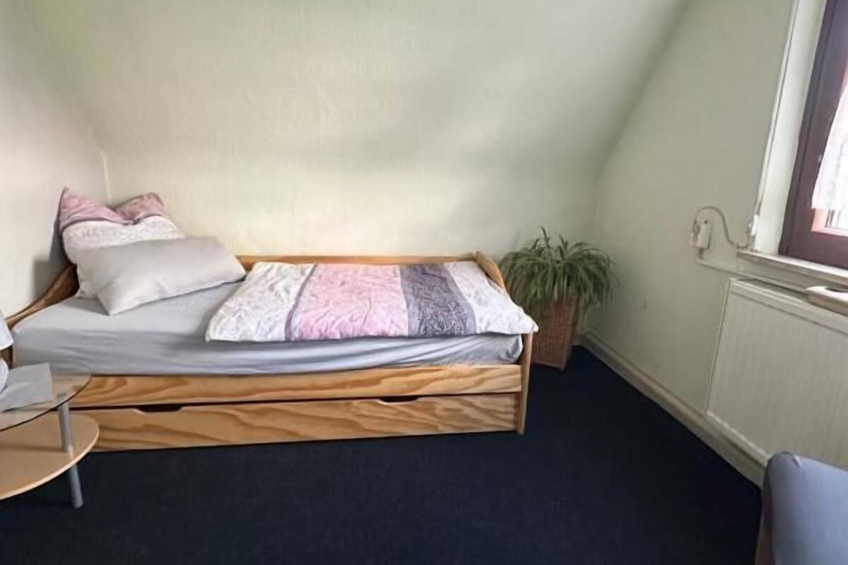 A small, cozy room with a loft bed, a small table, and a window.