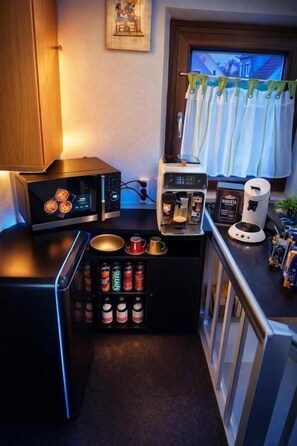 A compact kitchenette with a microwave, coffee maker, and a small fridge. There are canned beverages and a coffee pot on the counter. - Corner Haus RM1 (Schnaittach)