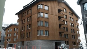 A multi-story building with a wooden facade and multiple balconies. - 2-bedroom apartment in serene Andermatt perfect for your getaway, with pool (Andermatt)