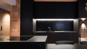 A modern kitchen with dark cabinetry, a stainless steel countertop, and a built-in oven. - 2-bedroom apartment in serene Andermatt perfect for your getaway, with pool (Andermatt)