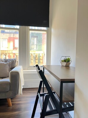 Une chambre moderne avec une table à manger, un canapé et une fenêtre donnant sur des immeubles.