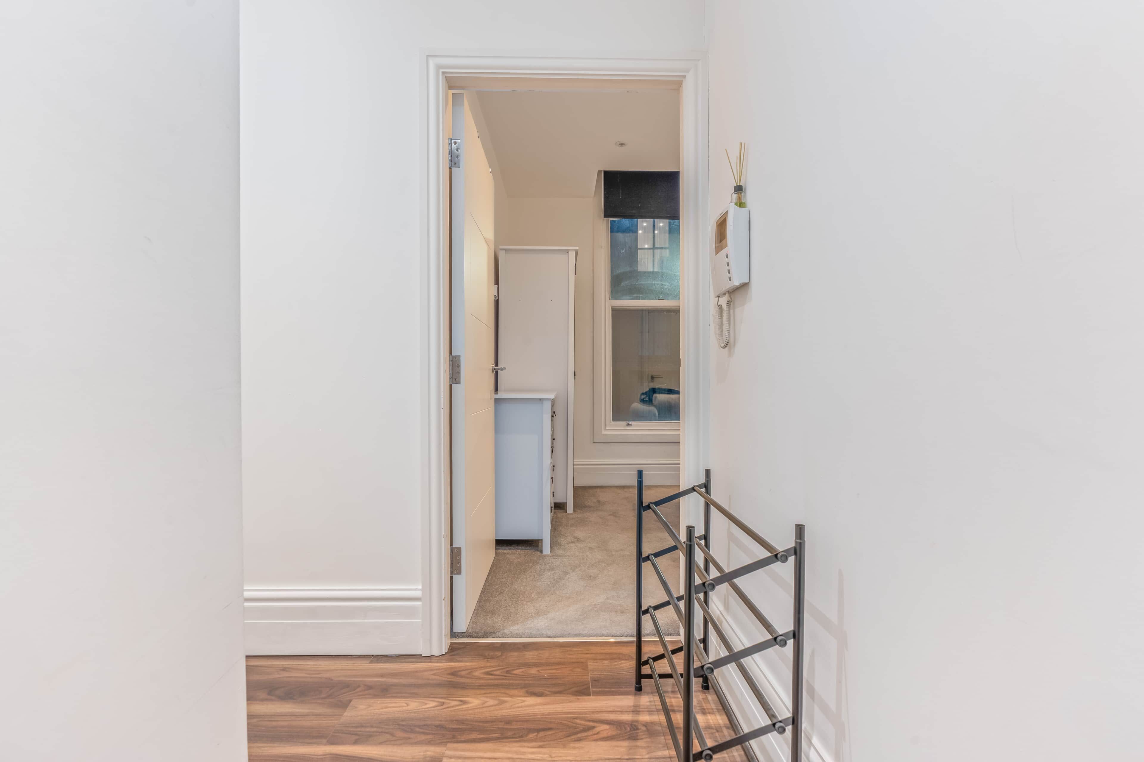 A hallway with a wooden floor, a white door, and a glass shower door.