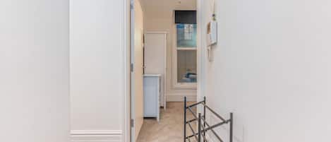A hallway with a wooden floor, a white door, and a glass shower door.