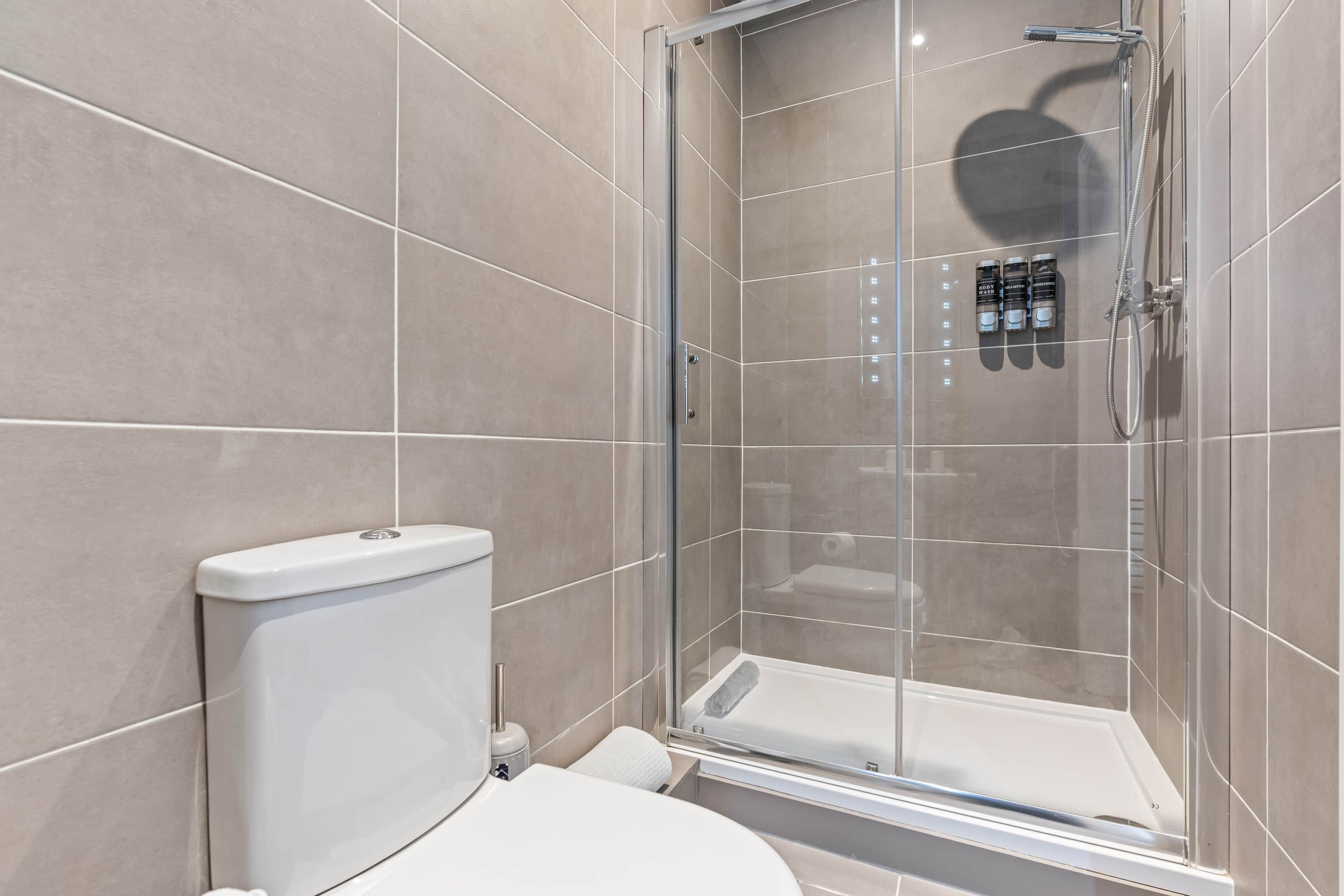 Une salle de bain moderne avec une douche à parois de verre, des toilettes et un lavabo.