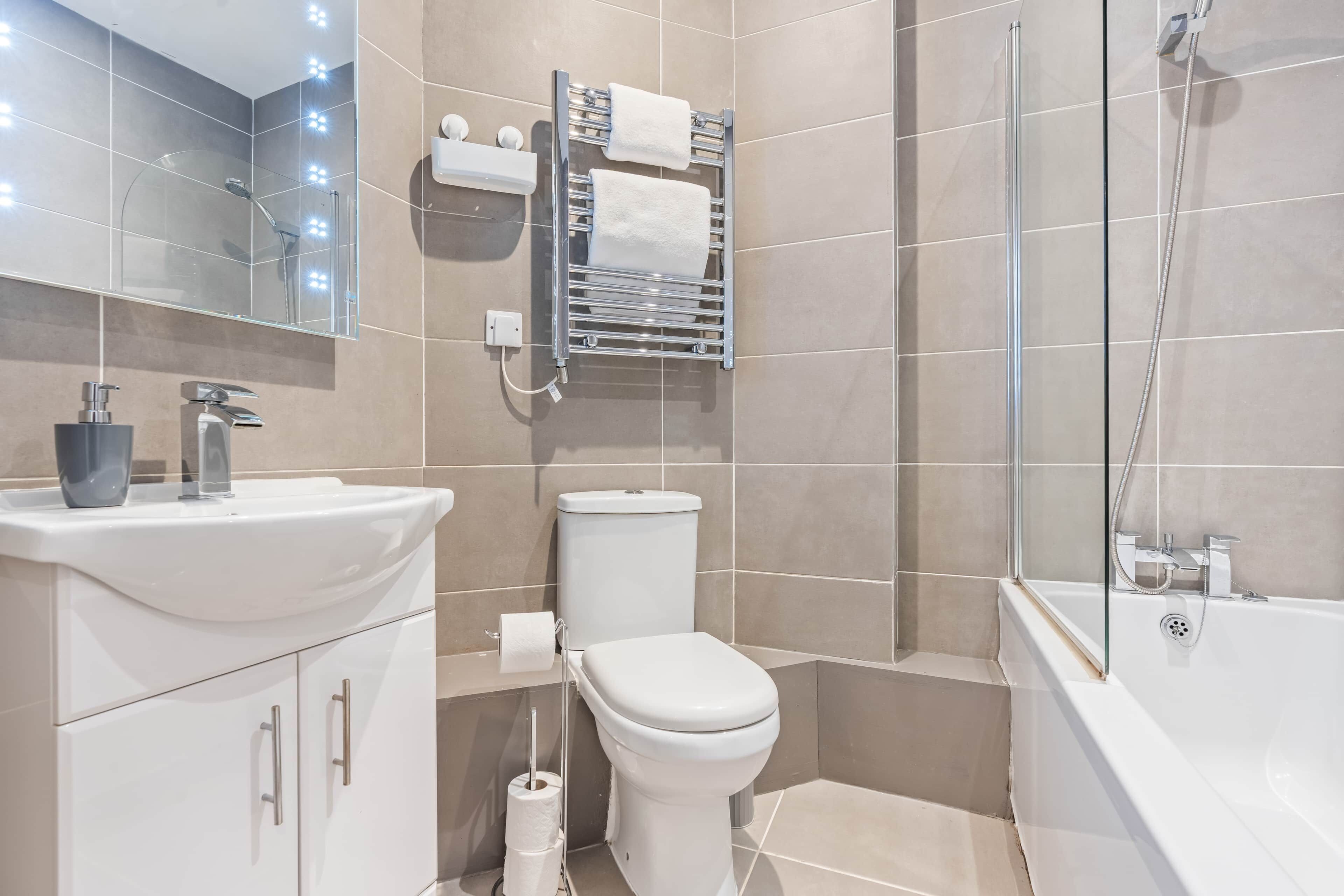 Ein modernes Badezimmer mit Waschbecken, Toilette und Badewanne, alles in Weiß.