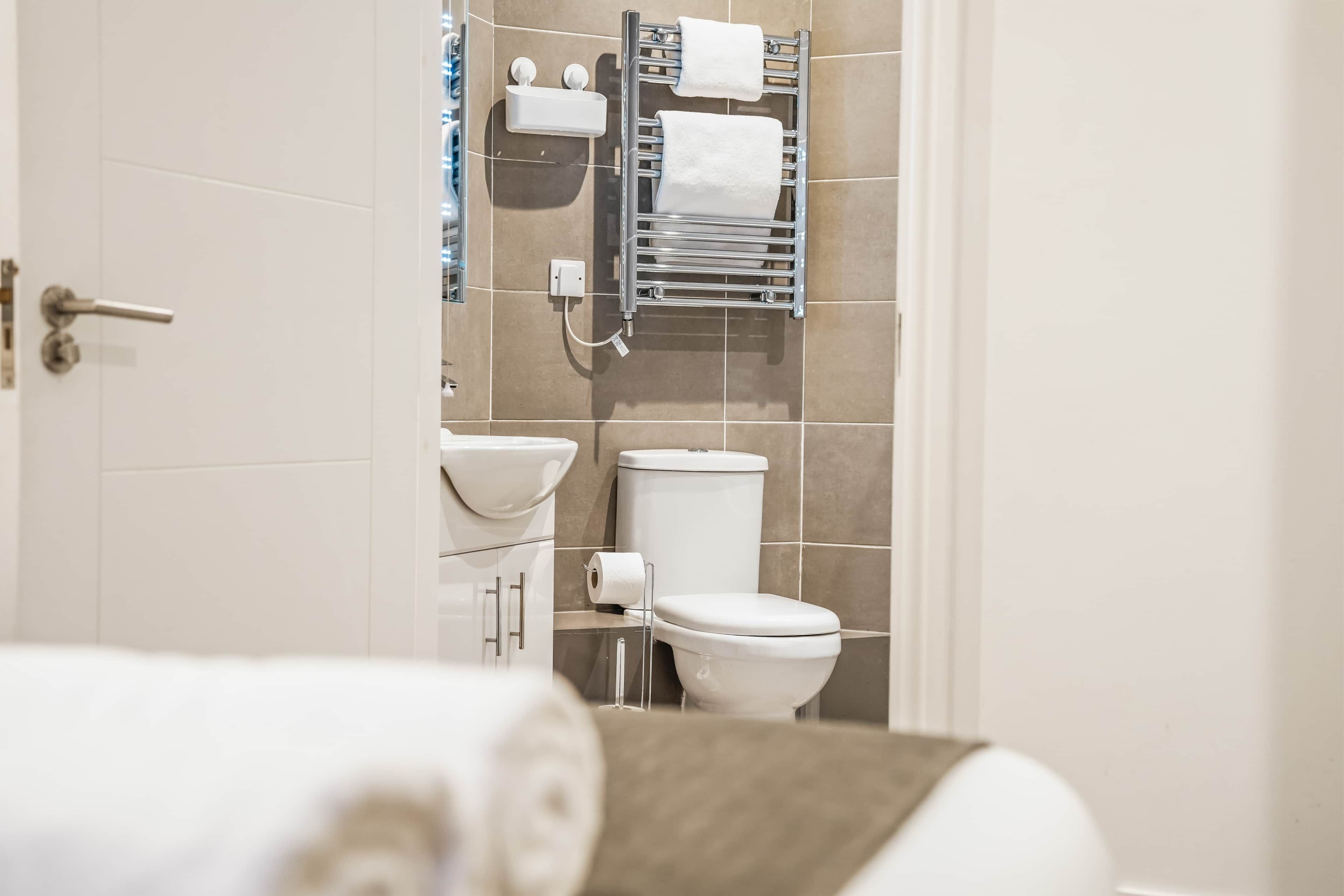 A modern bathroom with a toilet, sink, and towel rack.