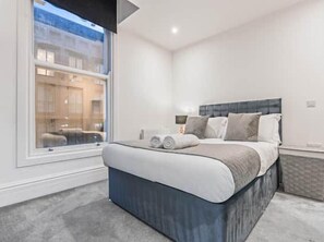 Une chambre moderne avec un grand lit, une fenêtre et une vue sur l’extérieur.