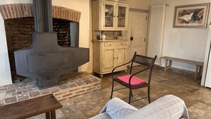 Ein gemütliches Wohnzimmer mit Kamin, einem Holzschrank, einer Bank und einem gepolsterten Sessel.