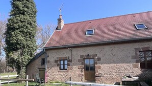 Ein Gebäude aus Stein mit rotem Dach, einer Holztür und einem kleinen Fenster.