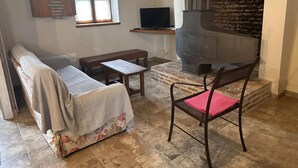 Ein gemütliches Wohnzimmer mit einer Couch, einer Bank, einem Tisch, einem Fernseher und einem Kaminofen.